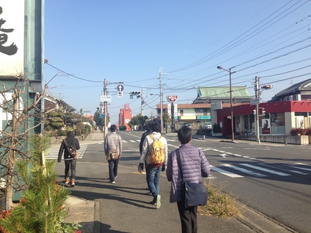 参加者が、久米河原東交差点付近の和菓子店の前の歩道を、東を向いて駅の方へ歩いている。
