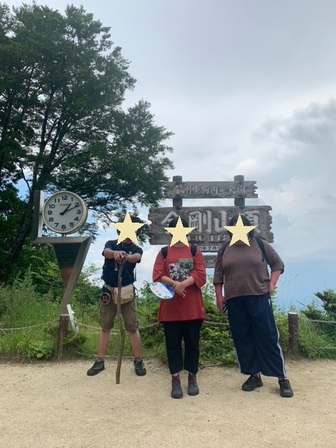 「金剛山頂」の標示の前にて、参加者3人で記念撮影。