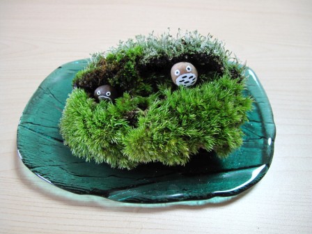 青緑色のガラスの皿に、苔とト◯ロ風に彩色した小石「トロちゃん」の寄せ植え